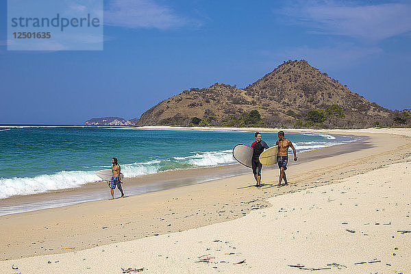 Surfer mit Brettern laufen an der Küste entlang. West Sumbawa.Indonesien.Indonesien