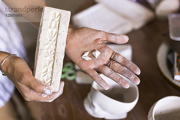 Frau Hand hält Tonziegel in Keramikwerkstatt