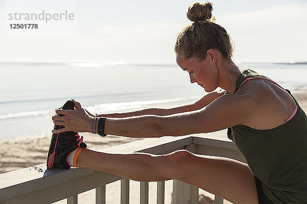 Frau macht Stretching auf Balkon in der Nähe von Strand