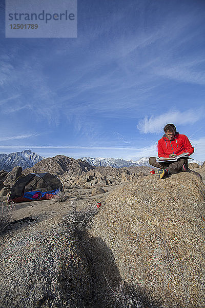 Ein Mann  der auf einem Felsbrocken in den Alabama Hills in der Nähe von Lone Pine  Kalifornien  seinen Gedanken nachhängt.