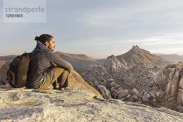 Ein junger Mann entspannt sich auf einem Felsen und erkundet die Wüstenlandschaft