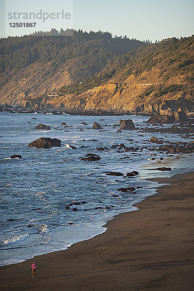 Eine Frau läuft entlang der felsigen Küste von Nordkalifornien