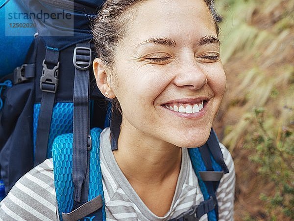 Eine lächelnde Frau mit einem Rucksack Wandern im Wald
