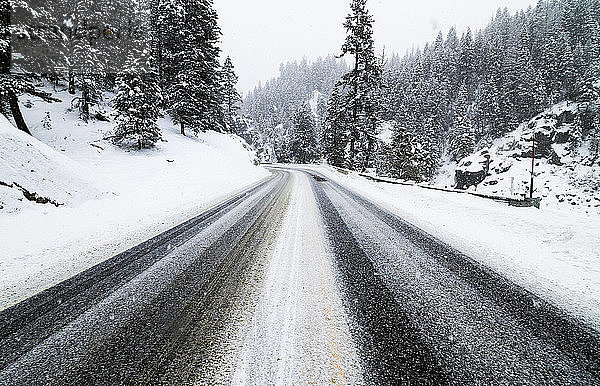 Eine verschneite Straße entlang einer winterlichen Gebirgspassage