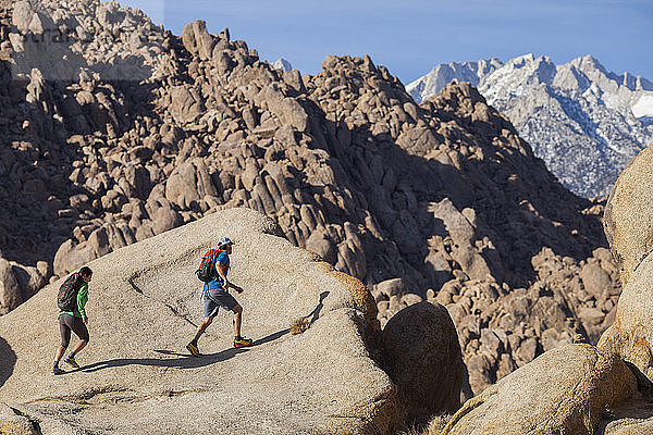 Ein Mann und eine Frau wandern auf riesigen Felsbrocken in den Alabama Hills an den Ausläufern der Sierra Nevada Mountains außerhalb von Lone Pine  Kalifornien  herum.