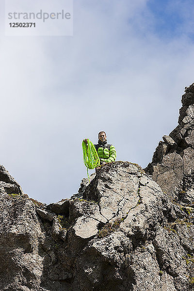 Ein Kletterer wirft ein Seil vor dem Abseilen von einer Klippe. Hnappavellir  Island.