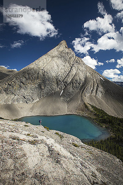 Entfernte Ansicht des Wanderers  der auf einem Felsen steht und den Coleman Lake erkundet