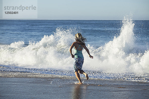 Eine erwachsene Frau beim Flirten mit den Wellen in Todos Santos  Mexiko