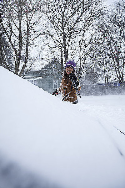 Eine erwachsene Frau  die Spaß daran hat  ihr Fahrzeug nach einer frischen Schneedecke abzuräumen