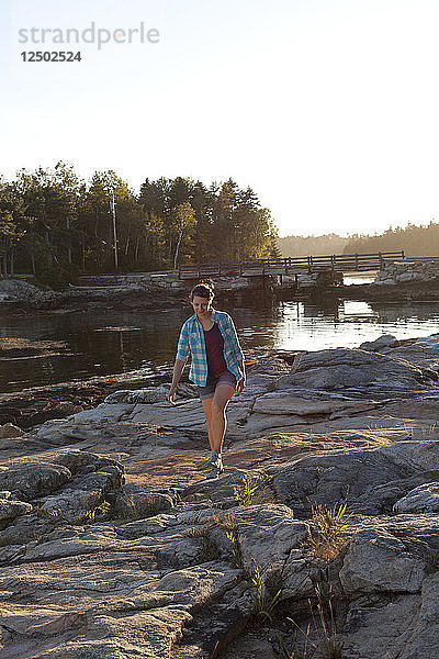 Frau geht bei Sonnenuntergang an den Felsen im Reid State Park entlang