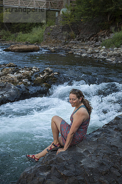 Eine Frau sitzt am Basaltufer des Spokane River im Riverside State Park  Washington.