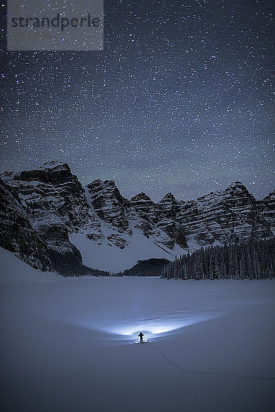 Beleuchtete Ansicht der Person Skifahren auf verschneite Landschaft unter Sternenhimmel in der Nähe von Moraine Lake