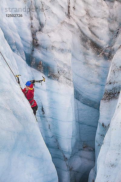 Ein Mann schwingt seine Eisgeräte  während er auf einer Tagestour mit St. Elias Alpine Guides zum Root Glacier im Wrangell-St. Elias National Park  Alaska  aus einer Gletschermühle klettert.