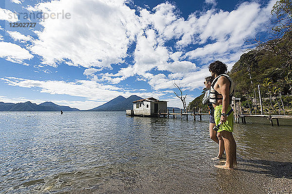 Junges Schwimmerpaar erkundet den Berg  während sie ihre Zehen in den See tauchen
