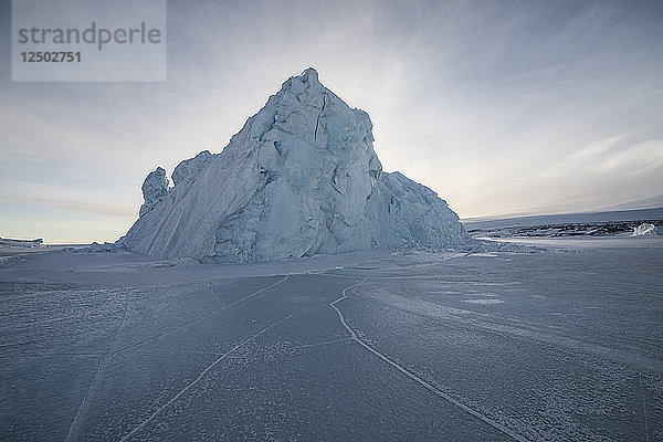 Ein im Meereis des Rossmeeres in der Antarktis eingefrorener Eisberg.