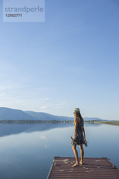 Frau  die am Rande eines hölzernen Docks mit Blick auf den Lake Pend Oreille steht  Sandpoint  Idaho