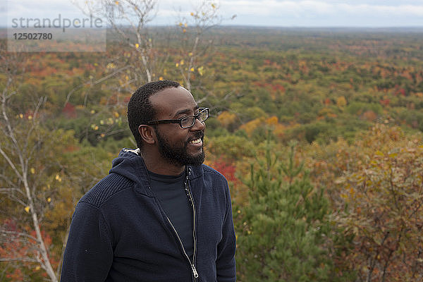 Lächelnder karibischer Mann auf dem Gipfel des Bradbury Mountain State Park an einem Herbsttag