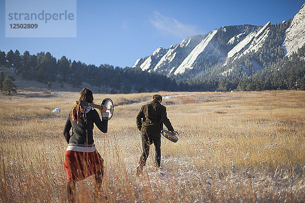 Die Musiker Ian Van Ornum (rechts) und Dani Aubert wandern mit ihrer Mandoline und ihrem Banjo unterhalb der Flatirons in Chautauqua  Boulder  Colorado.