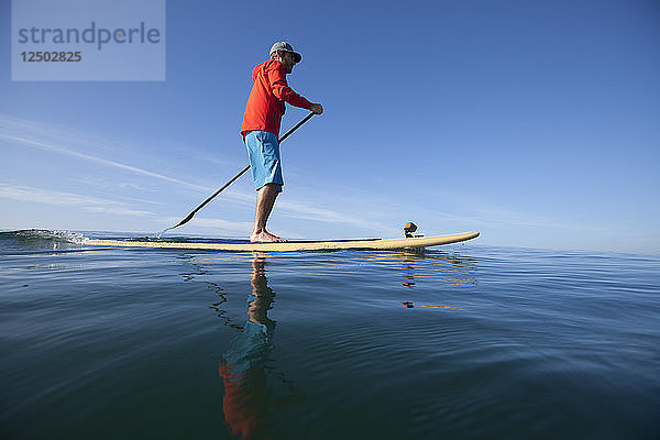 Ein erwachsener Mann  der mehrere Meilen vor der Küste von San Diego auf dem Pazifischen Ozean Stand Up Paddle Boarding betreibt.