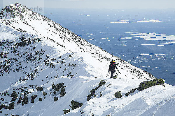 Ein Wanderer nähert sich dem Gipfel des Katahdin während einer Winterwanderung auf dem Knife Edge Trail im Baxter State Park  Maine.