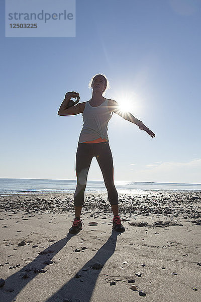 Frau macht Übung am Strand mit Kettlebell