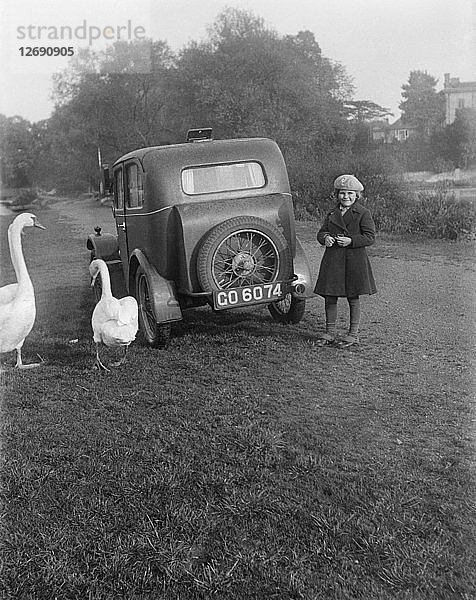 Ein junges Mädchen neben einem Auto  wahrscheinlich einem Austin 7  mit zwei Schwänen  um 1930. Künstler: Unbekannt.