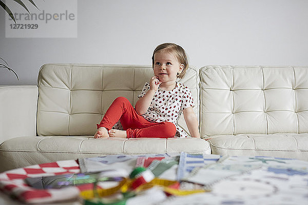 Thoughtful girl sitting on sofa at home