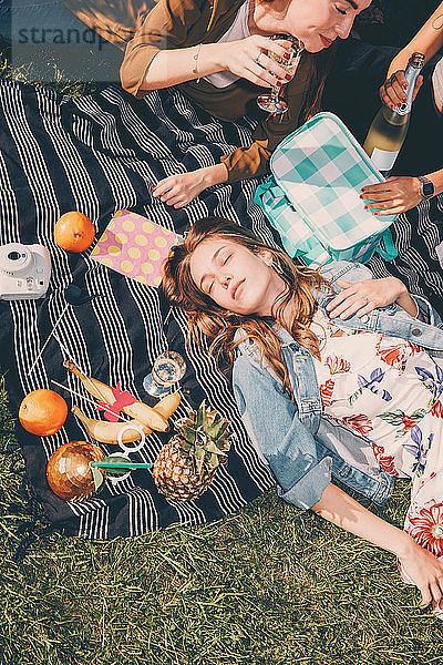 High angle view of young woman lying by friends enjoying picnic during summer at back yard