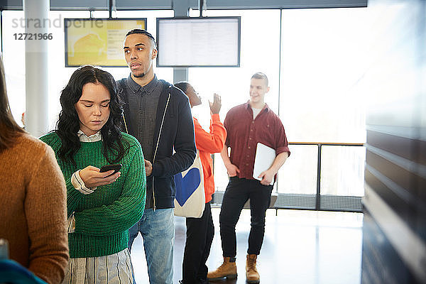 Male and female students standing in queue at university