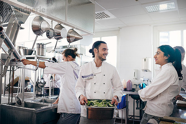 Male and female chefs communicating while preparing food in commercial kitchen
