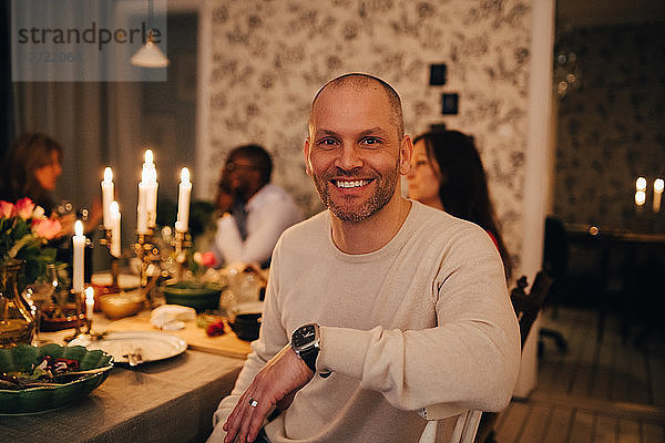 Portrait of mature man with friends at dining table in dinner party