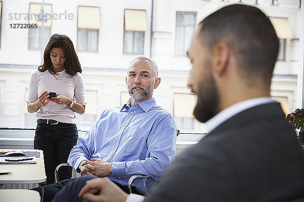 Mature businessman explaining with colleague in meeting at office