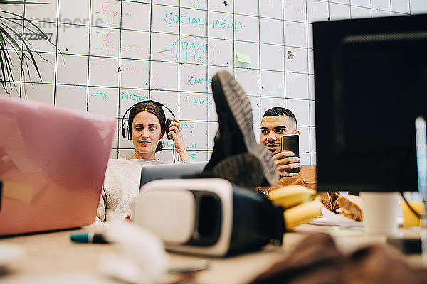 Young business colleagues sitting against tile wall at creative office