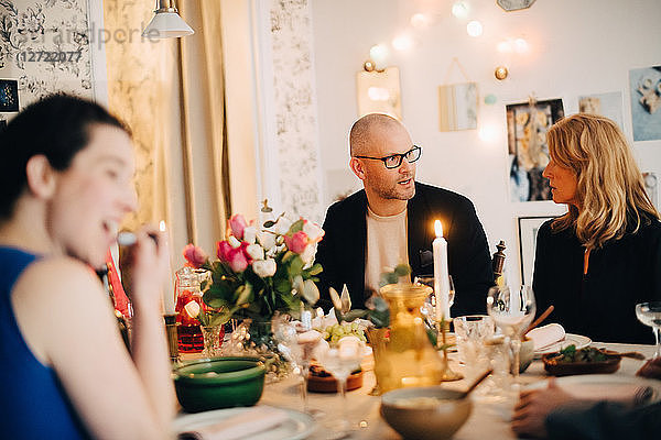 Mature friends talking while enjoying food at dinner party
