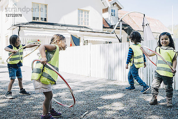 Full length of students playing with plastic hoops in playground