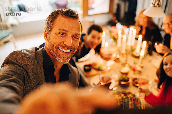 Mature man taking selfie with friends at dinner party