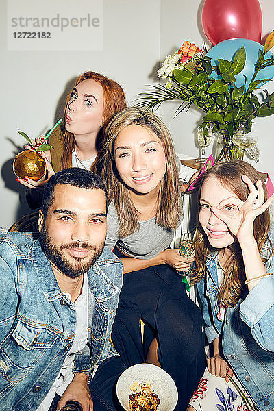 Portrait of smiling young multi-ethnic friends enjoying dinner party at apartment