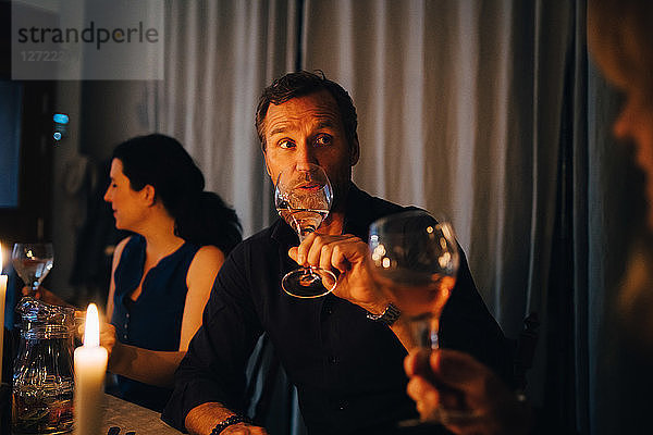 Man drinking wine while sitting with female friends at dinner party