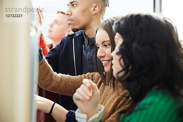 Smiling student looking at test results while standing with friends in university