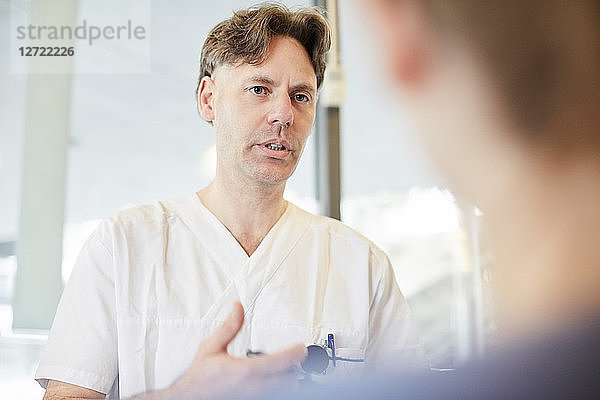 Mature male nurse discussing with female coworker at lobby in hospital