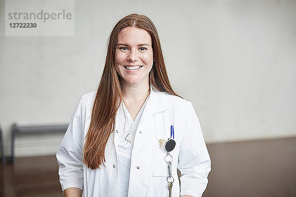 Portrait of smiling young female brunette doctor standing in corridor at hospital