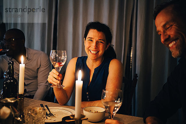 Happy woman enjoying dinner with male friends in party at home