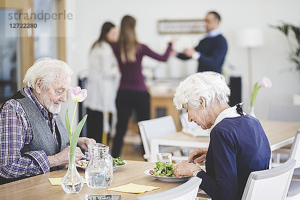 Senior couple eating lunch while at table in nursing home