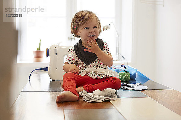 Full length of girl wearing scarf while sitting on table at home