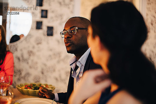 Close-up of mature man talking to friend during dinner party