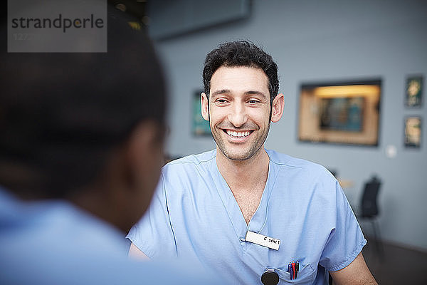 Smiling male nurse talking with coworker at cafeteria in hospital