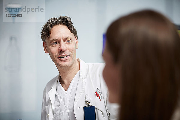 Smiling mature doctor looking at female coworker while sitting in hospital cafeteria