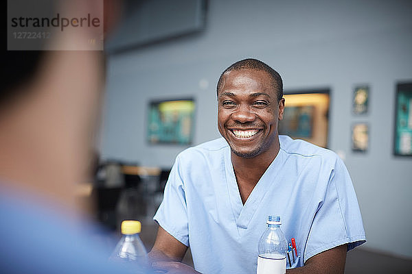 Smiling male nurse talking with coworker at hospital cafeteria