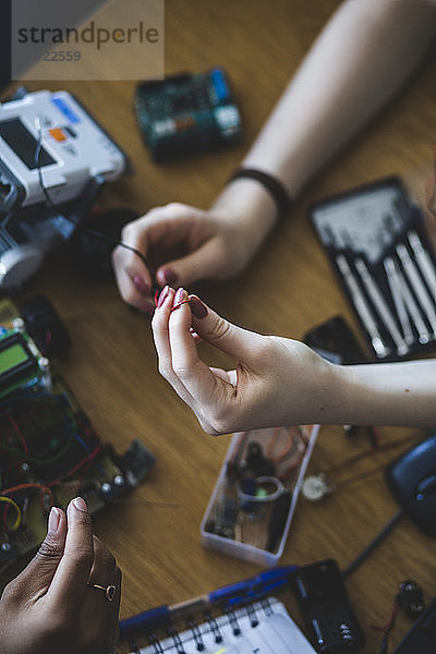 High angle view of female students preparing science project at desk in high school classroom