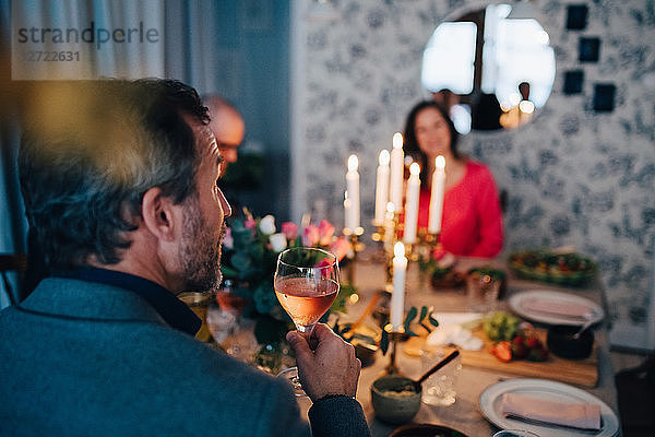 Mature man having wine while sitting with friends at dinner party